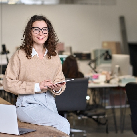 Senhora sentada em uma mesa a segurar uma tablet
